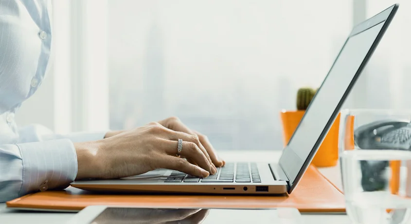 a woman typing on a laptop in an office.