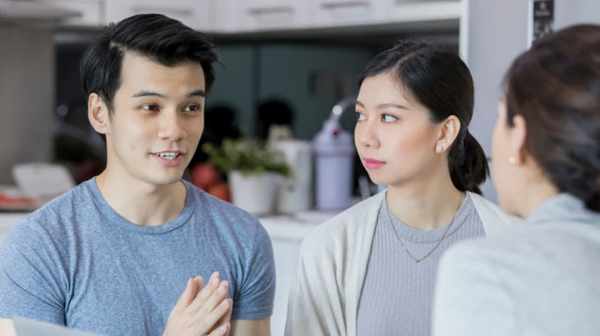 asian man and woman talking to each other in the kitchen.